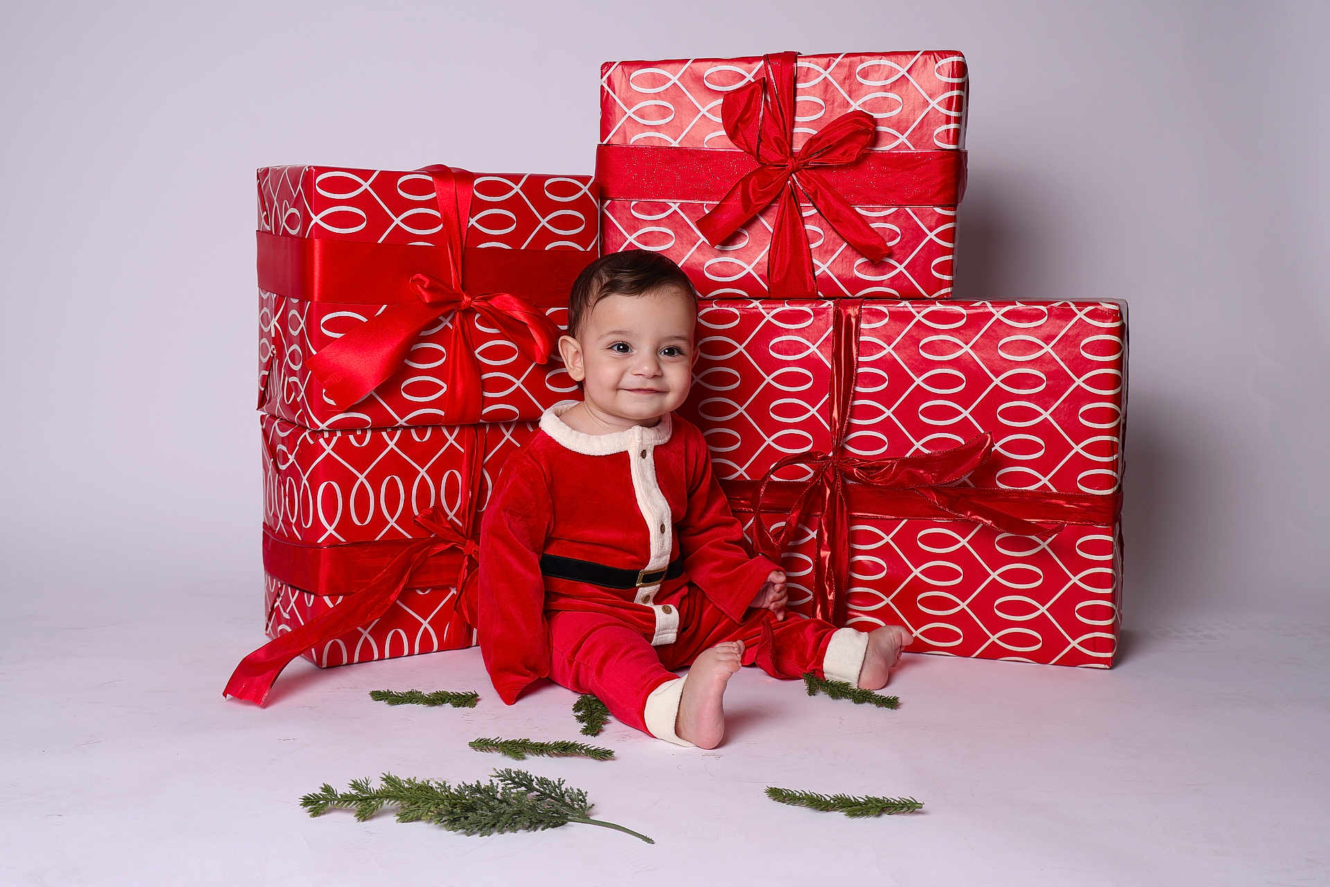 Armen is registered to the contest to win money with this photo: baby, child, red_outfit, santa_costume, presents, gift_wrap, ribbons, holiday, christmas, smile, sitting, greenery, indoor, studio, cute, festive, celebration, holiday_decor, portrait, happy