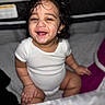 Jace is registered to the contest to win money with this photo: baby, child, smiling, curly_hair, onesie, indoor, sitting, happy, portrait, infant, cute, person, skin, face, hand, young, head, expression, bedroom, bedding