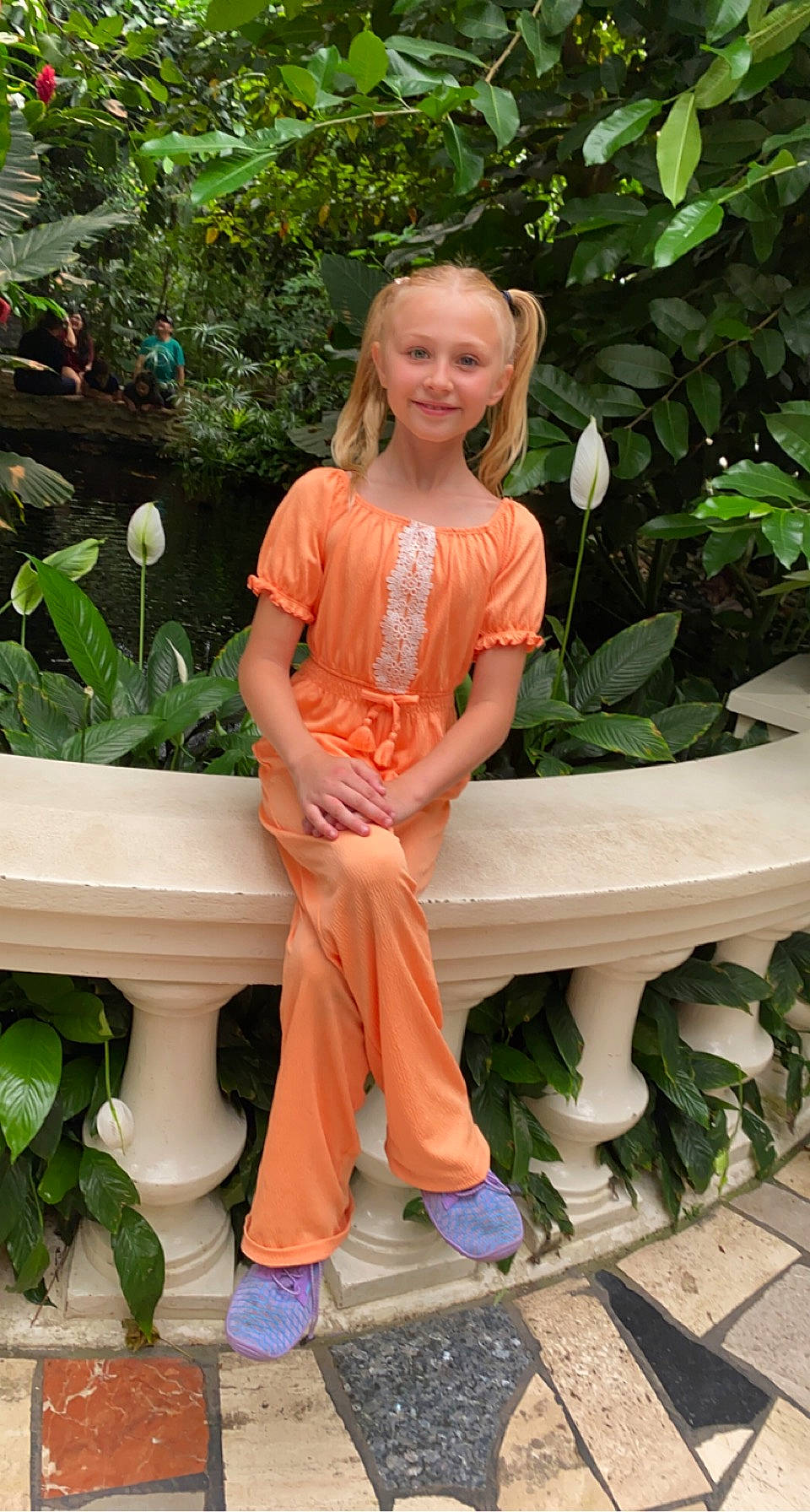 Kaylynn is registered to the contest to win money with this photo: baby_toddler_clothing, botany, face, flowerpot, garden, grass, green, happy, houseplant, joy, leaf, leisure, peach, person, plant, shoe, sitting, sleeve, smile, thigh