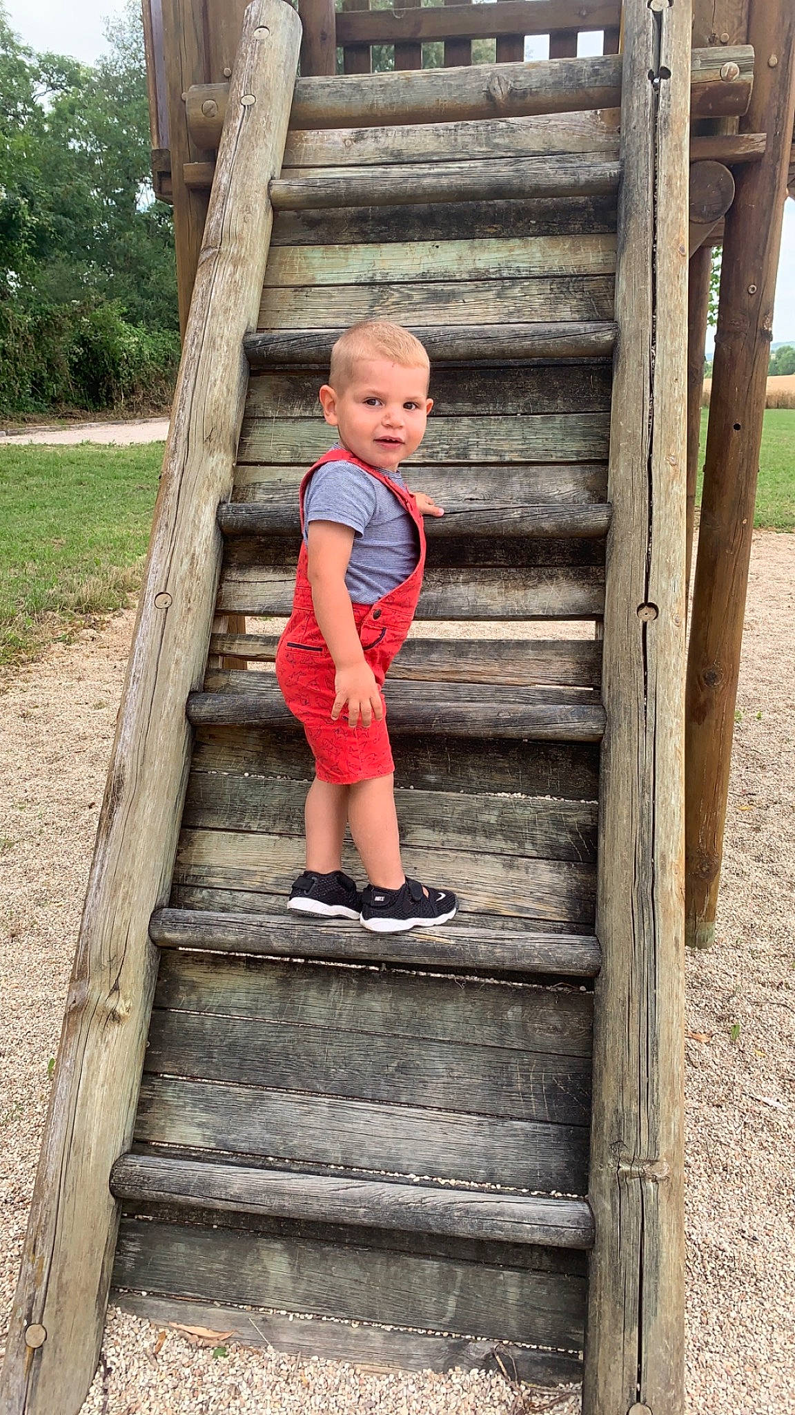 Tymaë participe au concours pour gagner de l'argent avec cette photo : baby_toddler_clothing, child, electric_blue, fun, grass, happy, human_body, human_leg, leg, leisure, people_in_nature, person, plant, shorts, sitting, stairs, standing, toddler, tree, wood