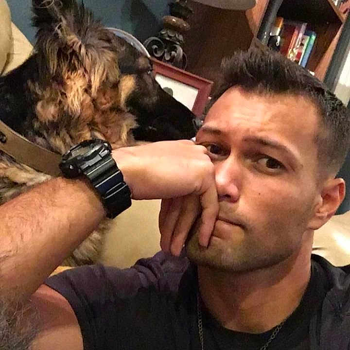 Max is registered to the contest to win money with this photo: bookcase, brown_dog, collar, couch, decor, dog, expression, face, furniture, home, indoor, man, portrait, relaxed, resting, shelf, short_hair, sitting, watch, watchband