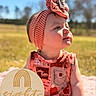 baby, child, outdoor, sunny, headband, coral, patterned_clothing, milestone, wooden_sign, rainbow_design, milestone_marker, sitting, grass, nature, portrait, cute, infant, pink_blanket, daylight, happy
