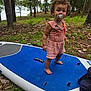 Sapphire joined the competition — help win amazing prizes! toddler, child, pacifier, curly_hair, barefoot, paddleboard, blue, forest, trees, grass, outdoor, nature, romper, pink_clothing, young_child, standing, playful, summer, daytime, person