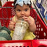 baby, child, shopping_cart, yellow_dress, blue_bow, headband, starbucks_cup, drink, store, aisle, sitting, cute, face, hands, person, retail, funny_expression, indoor, grocery, shopping