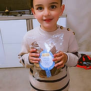 Mylan a rejoint le concours — aidez-le/la à gagner de superbes lots ! child, smiling, indoor, sweater, pants, chocolate, packaging, kitchen, cabinet, button, standing, happy, person, young, holding, food, treat, warm, cozy, portrait