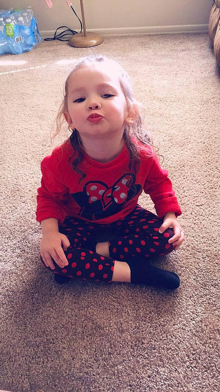 Kahlani is registered to the contest to win money with this photo: baby, blond, cheek, child, dress, eye, face, flooring, fun, head, leg, lip, nose, outerwear, person, play, red, sitting, skin, smile