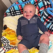 Caleb joined the competition — help win amazing prizes! baby, smiling, blanket, patterned_blanket, socks, indoor, child, clothing, cute, happy, portrait, infant, sitting, person, warm, cozy, head, face, human, soft