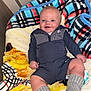 baby, smiling, blanket, patterned_blanket, socks, indoor, child, clothing, cute, happy, portrait, infant, sitting, person, warm, cozy, head, face, human, soft