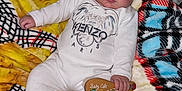 Caleb is registered to the contest to win money with this photo: baby, blanket, child, colorful, comfort, cute, face, footed_pajamas, fuzzy, head, holding, indoor, infant, onesie, person, plush, portrait, relaxing, smiling, wooden_paddle
