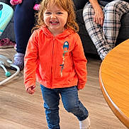 Layla Mae joined the competition — help win amazing prizes! adults, blonde_hair, child, couch, curly_hair, family, girl, happy, indoor, jeans, living_room, orange_jacket, portrait, smiling, socks, standing, stroller, table, toddler, wooden_floor
