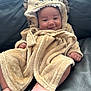 baby, infant, smile, face, lion_hood, bathrobe, plush, soft, cute, child, person, skin, foot, hand, couch, leather, relaxing, indoors, comfort, cozy