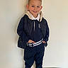 Mario a rejoint le concours — aidez-le/la à gagner de superbes lots ! belt, boy, casual_clothing, child, confident, cute, fashion, full_body, hands_in_pockets, indoor, navy_outfit, plain_background, portrait, quilted_vest, short_hair, smile, sneakers, spiky_hair, standing, white_collar