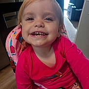 Aurora is registered to the contest to win money with this photo: toddler, child, smile, face, indoor, pink_clothing, backpack, chair, person, happy, young_child, hair, eyes, mouth, teeth, furniture, floor, window, light, casual