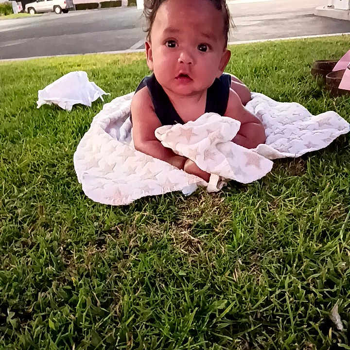 Jacob Woods is registered to the contest to win money with this photo: baby, child, infant, grass, outdoor, blanket, star_pattern, lying_down, portrait, face, curious, eyes, black_hair, park, lawn, street, gas_station, daylight, photography, safe