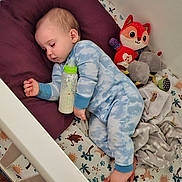 Cash is registered to the contest to win money with this photo: baby, sleeping, pajamas, milk_bottle, crib, pillow, stuffed_toy, blanket, bedtime, child, indoor, peaceful, cute, infant, animal_print, foot, hand, soft_toys, nursery, cozy