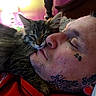 Dakit is registered to the contest to win money with this photo: cat, kitten, man, face, tattoo, close_up, sleeping, cuddle, fur, whiskers, nose, ear, red_clothing, indoor, bedroom, lamp, soft_light, relaxation, compassion, affection