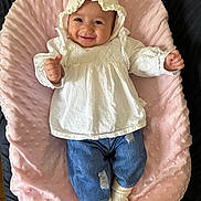 Juliana joined the competition — help win amazing prizes! baby, smiling, white_bonnet, white_blouse, denim_pants, ripped_jeans, white_socks, pink_cushion, soft_texture, infant, happy, portrait, laying_down, indoors, child, cute, clothing, face, person, comfortable