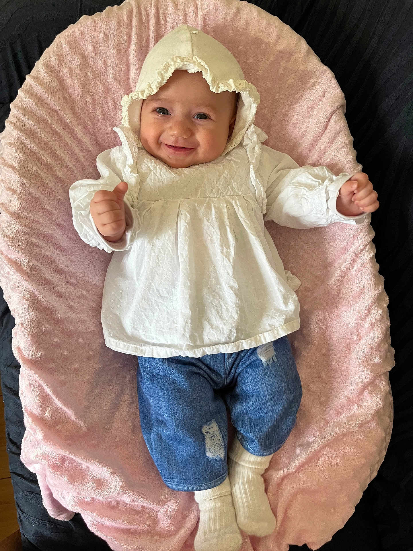 Juliana joined the competition — help win amazing prizes! baby, smiling, white_bonnet, white_blouse, denim_pants, ripped_jeans, white_socks, pink_cushion, soft_texture, infant, happy, portrait, laying_down, indoors, child, cute, clothing, face, person, comfortable