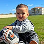 Raphaël participe au concours pour gagner de l'argent avec cette photo : toddler, child, soccer_ball, grass, outdoor, smiling, happy, casual_clothing, overalls, footwear, sunny, daylight, playing, park, blue_sky, short_hair, young_child, hands, face, expression