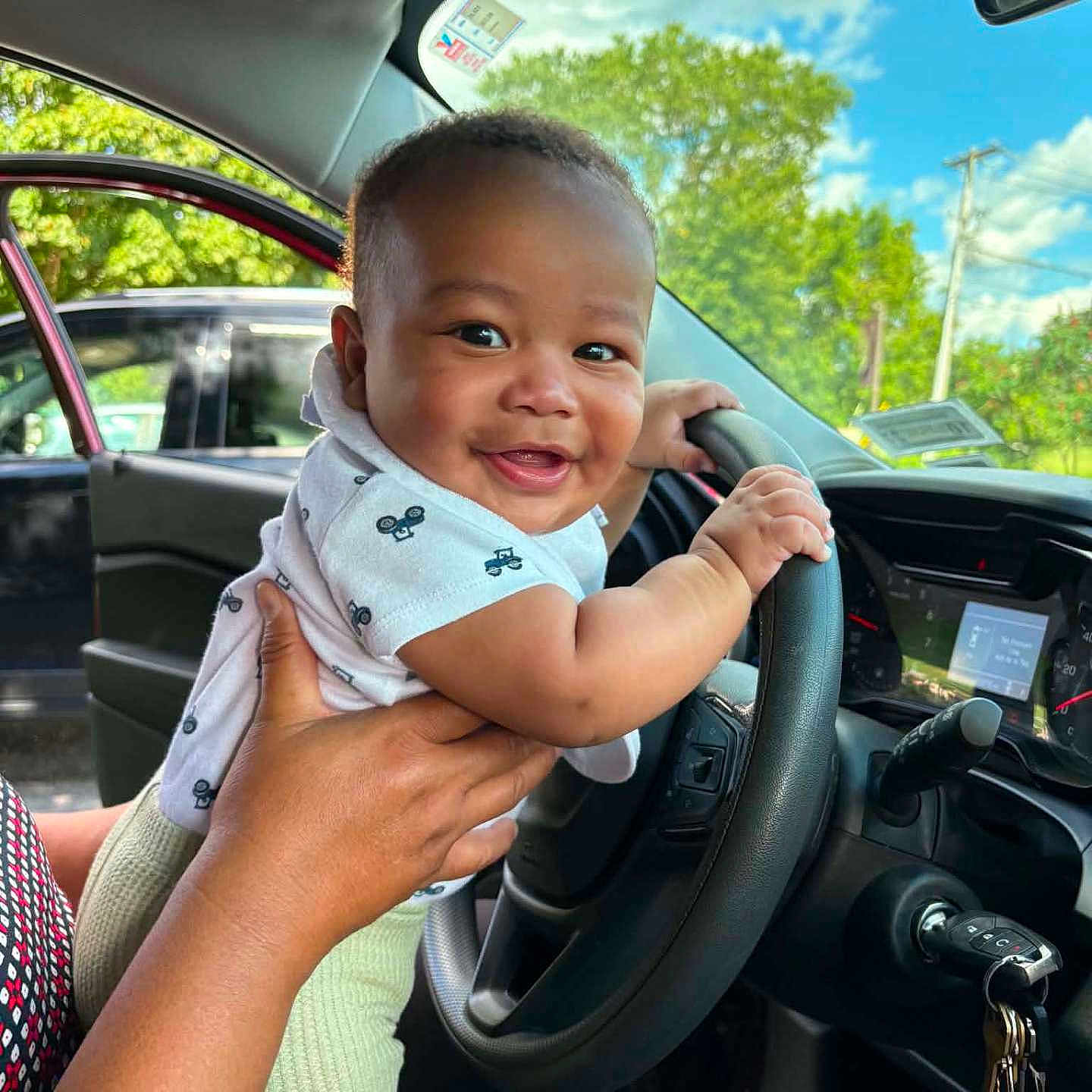 Jaevon joined the competition — help win amazing prizes! adult_hand, automobile, baby, blue_sky, car, child, closeup, clouds, dashboard, driver_seat, family, happy, infant, outdoor, portrait, short_sleeves, smiling, steering_wheel, trees, vehicle
