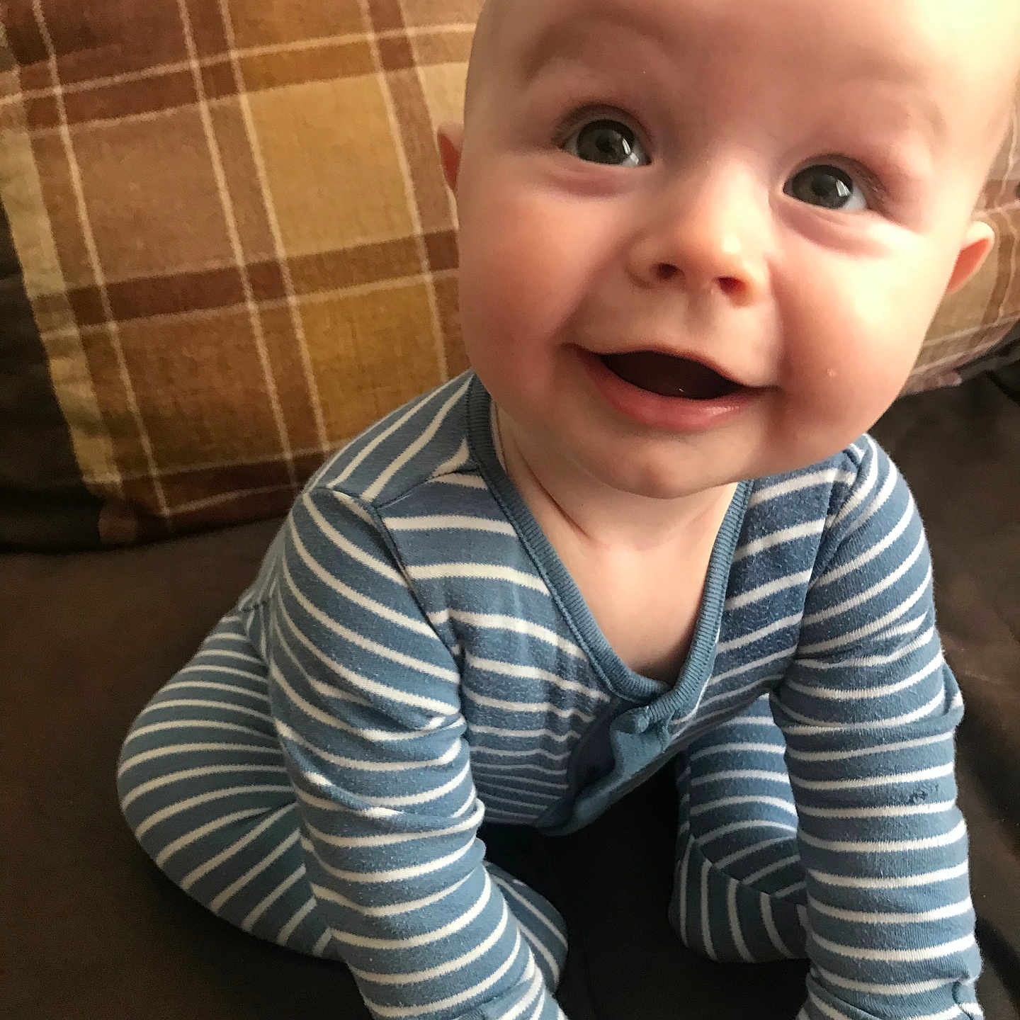 Grayson-Charlie is registered to the contest to win money with this photo: baby, blue_clothing, child, couch, cute, eyes, face, furniture, hand, happy, human, indoor, infant, mouth, onesie, plaid_pillow, sitting, skin, smiling, striped_clothing
