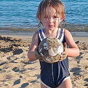 Mya a rejoint le concours — aidez-le/la à gagner de superbes lots ! child, beach, sand, water, sea, wet_hair, soccer_ball, summer, outdoor, play, fun, sandy_hands, sunlight, vacation, swimsuit, shore, young, person, nature, recreation