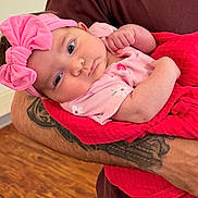 Raylynn joined the competition — help win amazing prizes! baby, infant, pink_bow, blanket, tattoo, arm, holding, curious, indoors, wooden_floor, clothing, person, cute, headband, portrait, newborn, skin, face, expression, cozy
