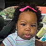 baby, child, infant, portrait, car, car_interior, car_seat, curly_hair, pink_bow, headband, tongue_out, facial_expression, smiling, brown_eyes, earrings, striped_shirt, sitting, indoors, vehicle, closeup