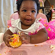 Naela is registered to the contest to win money with this photo: baby, child, infant, portrait, smiling, happy, eating, cake, frosting, pink_dress, bow, curly_hair, high_chair, indoor, home, birthday, food, messy, hands, family