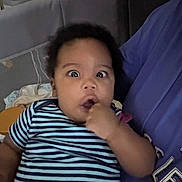 Naela joined the competition — help win amazing prizes! baby, casual, child, comfort, couch, curly_hair, expression, face, finger, hand, holding, home, indoor, infant, person, purple_shirt, seated, striped_shirt, upset, wide_eyes