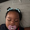 Naela joined the competition — help win amazing prizes! baby, sleeping, pacifier, bows, hair, curly_hair, portrait, close_up, face, child, indoors, bed, pillow, blanket, dark_clothing, red_clothing, blue_accessories, resting, peaceful, photography