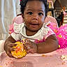 baby, child, infant, smiling, happy, portrait, high_chair, cake, frosting, food, eating, messy, pink, dress, bow, curly_hair, indoor, kitchen, birthday, celebration