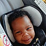 Naela is registered to the contest to win money with this photo: baby, child, smiling, face, car_seat, curly_hair, safety, infant, seatbelt, warning_label, cushion, closeup, portrait, cute, happy, person, indoors, seat, straps, young
