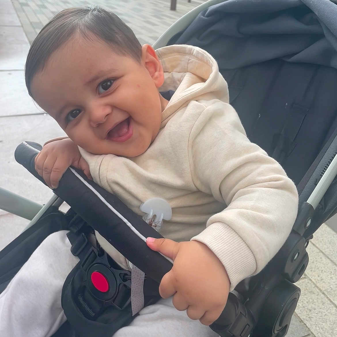 Jibril a rejoint le concours — aidez-le/la à gagner de superbes lots ! baby, black_hair, child, clothing, cute, daylight, expression, face, hand, happy, hoodie, infant, leisure, outdoor, person, playful, seatbelt, sitting, smile, stroller