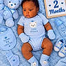 baby, infant, child, portrait, lying_down, blue, teddy_bear, blanket, plush_toy, baby_bottle, bib, mittens, socks, shoes, onesie, nursery, milestone, two_months, royal_theme, indoors
