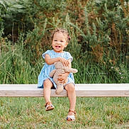 Zohra participe au concours pour gagner de l'argent avec cette photo : toddler, child, smiling, blue_dress, teddy_bear, bench, outdoor, greenery, grass, happy, cute, sandals, person, nature, daylight, portrait, young_child, sitting, toy, playful