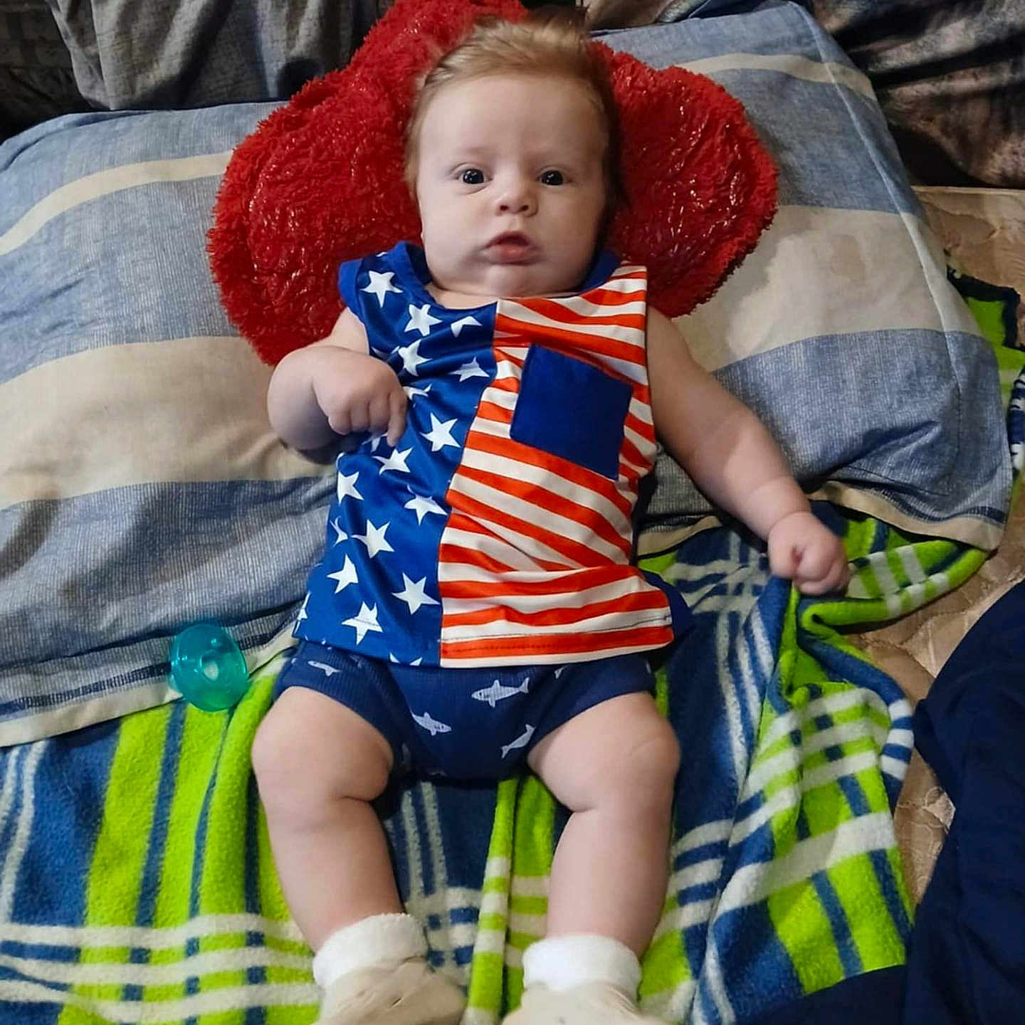 Grayson joined the competition — help win amazing prizes! american_flag, baby, bed, blanket, blue, child, clothing, cute, footwear, indoor, infant, lying_down, pacifier, person, pillow, portrait, red, stars, stripes, white