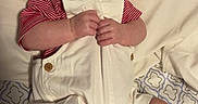 Hudson is registered to the contest to win money with this photo: baby, infant, overalls, striped_shirt, blanket, bed, bedding, hands, feet, face, expression, curious, lying_down, indoors, child, cute, person, young, skin, clothing