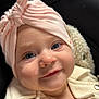 baby, infant, portrait, close_up, hat, headwrap, pink_headwrap, blue_eyes, smile, rosy_cheeks, eyelashes, cozy, blanket, jacket, button, fuzzy_texture, car_seat, black_background, soft_lighting, adorable