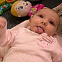 Julie joined the competition — help win amazing prizes! baby, infant, pink_clothing, tongue_out, toy_doll, musical_toy, blanket, playtime, cute, smiling, lying_down, child, indoor, soft_lighting, closeup, expression, person, face, happy, fun