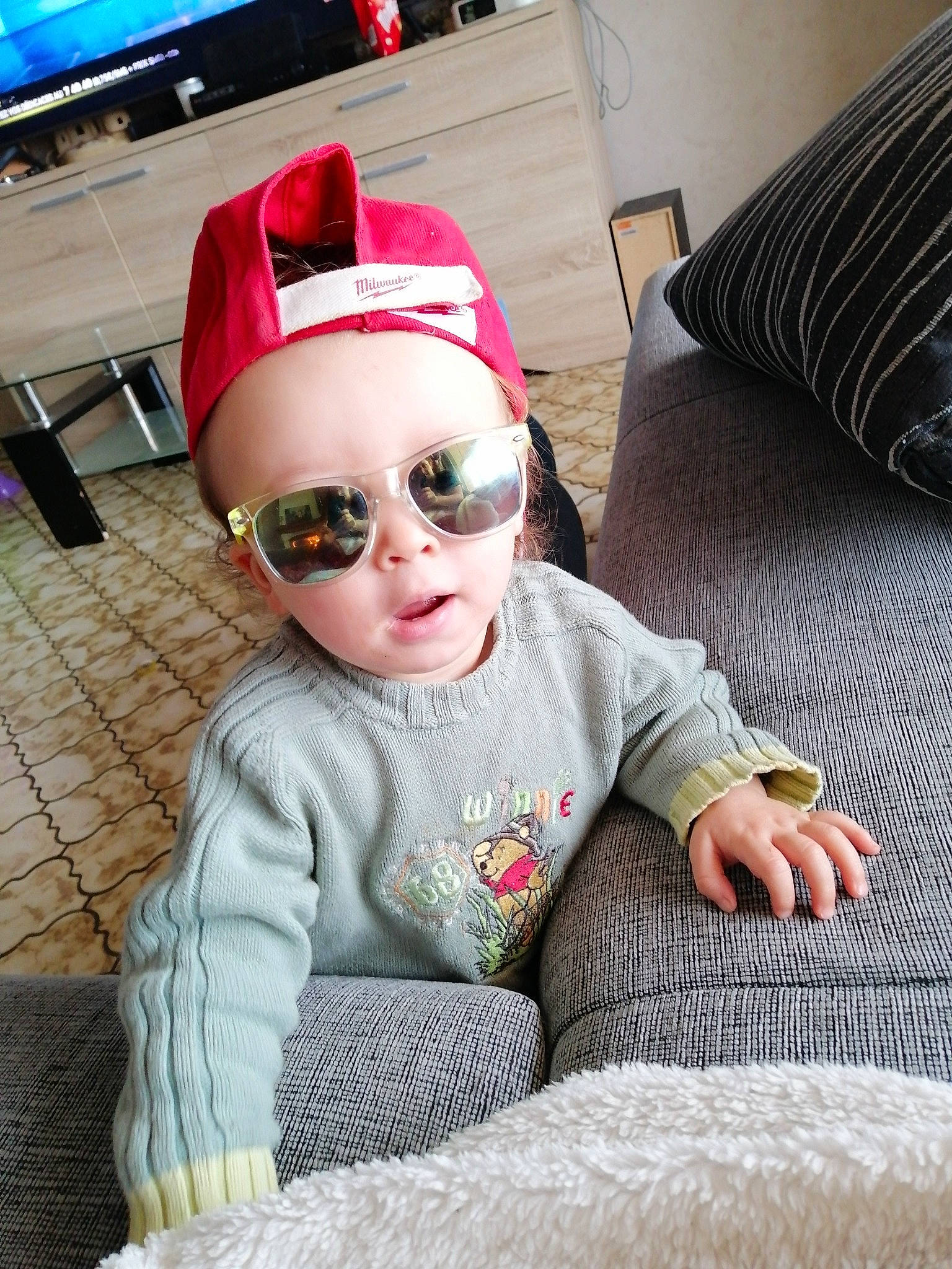 Lylio participe au concours pour gagner de l'argent avec cette photo : baby, baby_toddler_clothing, cap, child, comfort, cool, eyewear, flooring, fun, glasses, goggles, headgear, magenta, person, personal_protective_equipment, sleeve, sunglasses, television, textile, toddler