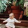 baby, child, smiling, sitting, plants, greenery, terracotta_pot, indoors, concrete_floor, cute, happy, infant, portrait, natural_light, casual_clothing, shorts, shirt, barefoot, toddler, playful