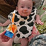baby, infant, bib, food, spoon, hand, quilt, blanket, bed, feeding, messy, orange_food, clothing, person, face, smile, socks, indoor, cute, child
