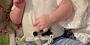 Hunter is registered to the contest to win money with this photo: baby, child, smiling, clothing, pacifier, beads, quilt, blanket, striped_pants, white_shirt, lying_down, happy, infant, cute, indoor, soft_toy, sock, face, hand, closeup