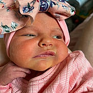 Ava-Rose is registered to the contest to win money with this photo: baby, infant, face, headband, bow, pink_clothing, closeup, skin, cheeks, expression, newborn, hand, portrait, cute, child, person, apparel, soft_lighting, indoors, fabric