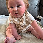 Teddy joined the competition — help win amazing prizes! baby, child, infant, sitting, blanket, couch, indoors, curly_hair, rosy_cheeks, clothing, cute, portrait, soft_texture, person, furniture, toddler, skin, face, expression, young