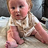 baby, child, infant, sitting, blanket, couch, indoors, curly_hair, rosy_cheeks, clothing, cute, portrait, soft_texture, person, furniture, toddler, skin, face, expression, young