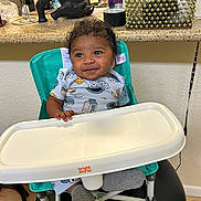 Braxton joined the competition — help win amazing prizes! baby, high_chair, smiling, curly_hair, cookie_monster, socks, kitchen, counter, elephant_statue, decorative_basket, plastic_tray, child, indoor, person, furniture, table, seat, cute, happy, young_child