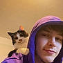 Luna is registered to the contest to win money with this photo: person, cat, hoodie, purple_clothing, indoor, pet, shoulder, face, smile, young_adult, feline, casual, ceiling_light, relaxed, closeup, companion, curious, domestic_animal, home, portrait