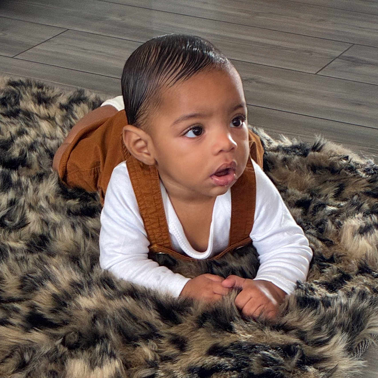 Yuriye joined the competition — help win amazing prizes! baby, brown_overalls, child, clothing, curious, expression, eyes, face, flooring, fur_rug, hair, hands, head, indoor, infant, lying_down, portrait, skin, white_shirt, young_child
